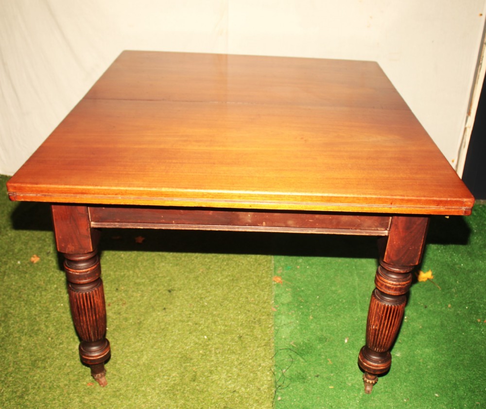 A late Victorian mahogany extending dining table featuring reeded turned legs on castors with a rectangular top.
