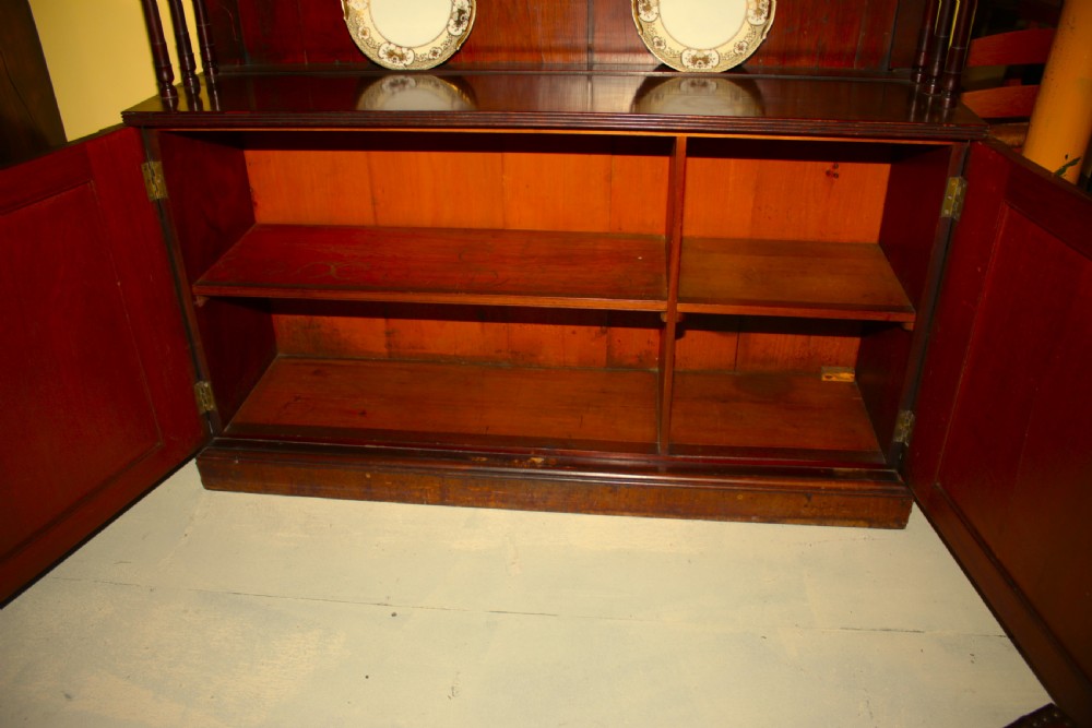 A Regency mahogany waterfall bookcase featuring open graduated shelves with turned spindle columns above a two-door base cupboard. View V
