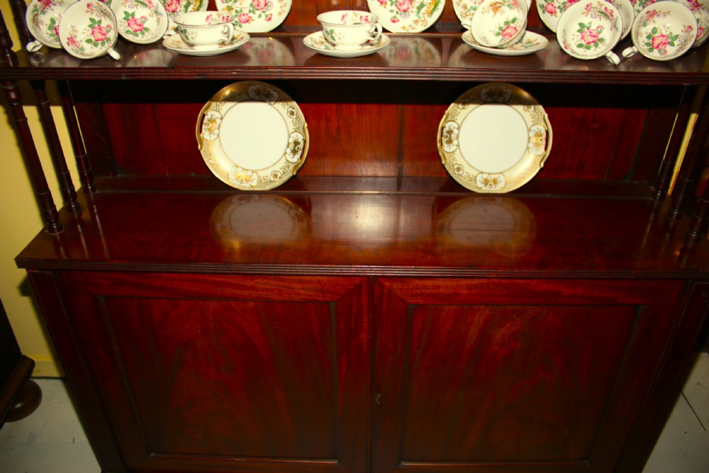 A Regency mahogany waterfall bookcase featuring open graduated shelves with turned spindle columns above a two-door base cupboard. View VII