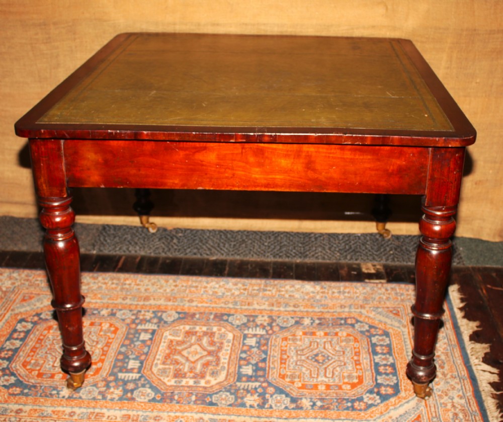 A William IV mahogany library desk featuring an inset leather top, two frieze drawers with turned wooden knobs, turned legs, and brass castors. View III