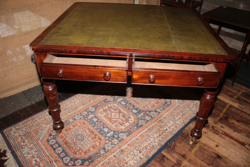 A William IV mahogany library desk featuring an inset leather top, two frieze drawers with turned wooden knobs, turned legs, and brass castors. View V