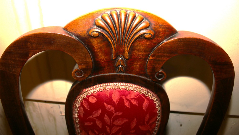 A set of six dark mahogany Queen Anne style dining chairs featuring carved shell crests and red patterned fabric upholstery. View III