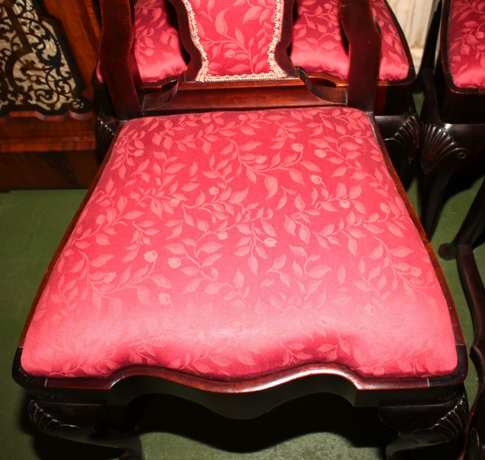 A set of six dark mahogany Queen Anne style dining chairs featuring carved shell crests and red patterned fabric upholstery. View VIII
