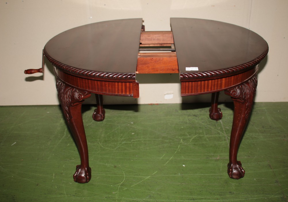 An oval mahogany extendable dining table with carved cabriole legs, ball and claw feet, and a winding handle mechanism. View IV