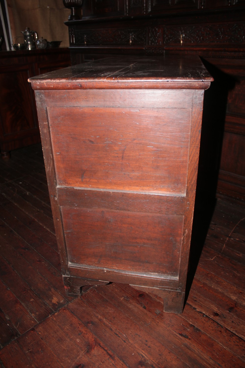 A late seventeenth-century dark oak chest of four drawers featuring raised geometric panel mouldings and brass drop handles. View VI