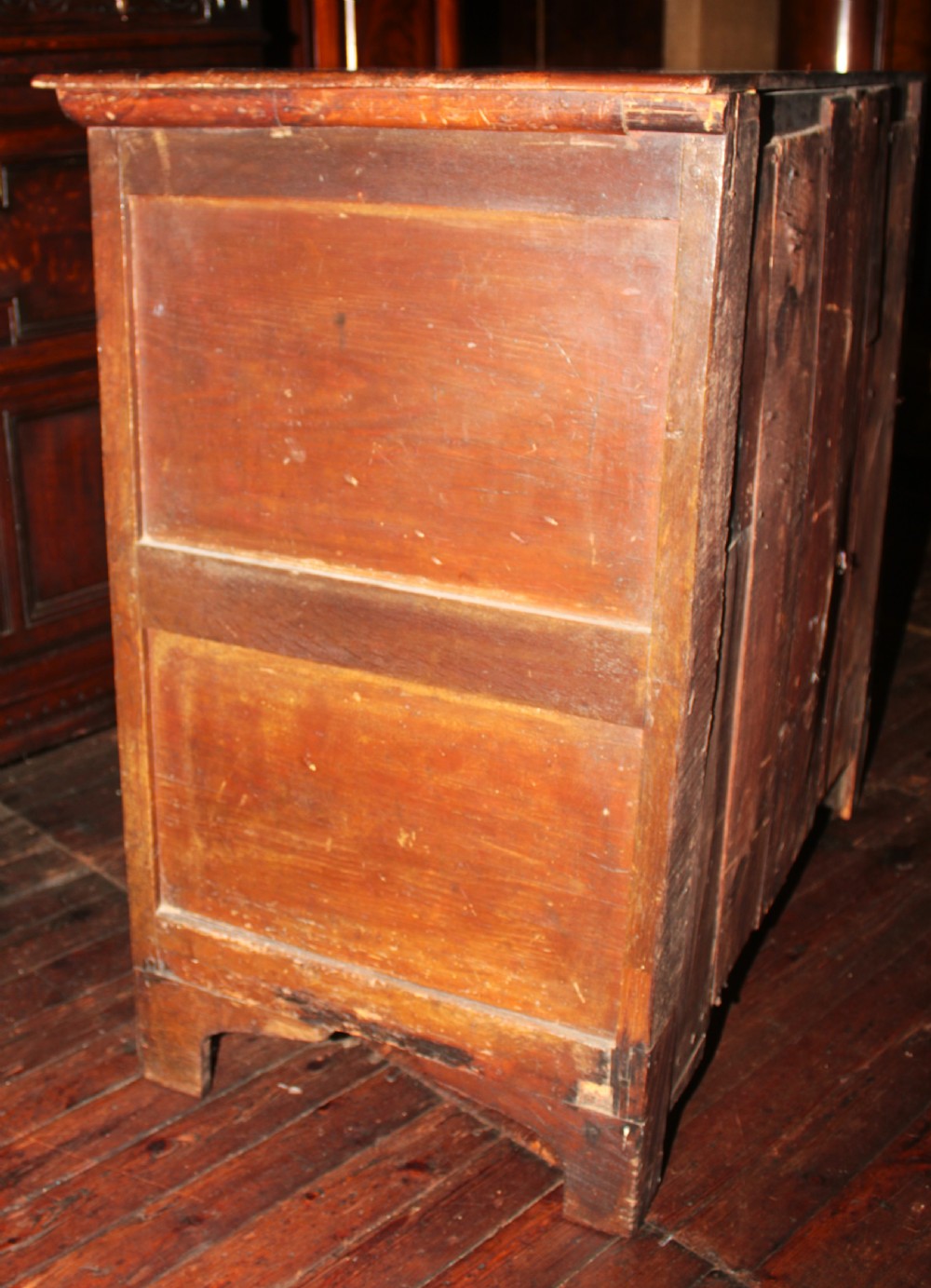 A late seventeenth-century dark oak chest of four drawers featuring raised geometric panel mouldings and brass drop handles. View IX