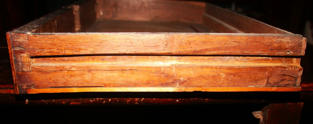 A late seventeenth-century dark oak chest of four drawers featuring raised geometric panel mouldings and brass drop handles. View XII