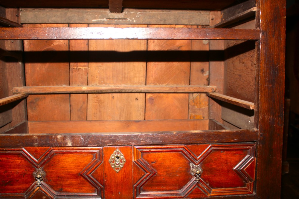 A late seventeenth-century dark oak chest of four drawers featuring raised geometric panel mouldings and brass drop handles. View XIII