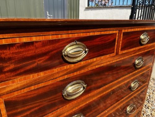 An Edwardian mahogany tall chest featuring two short drawers above four long drawers with satinwood crossbanding and brass oval drop handles. View XII