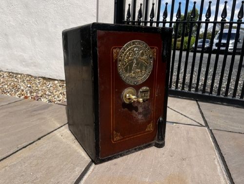A Victorian cast iron safe featuring a black outer body, maroon door with gold pinstriping, and a round brass Cyrus Price & Co maker badge. View II