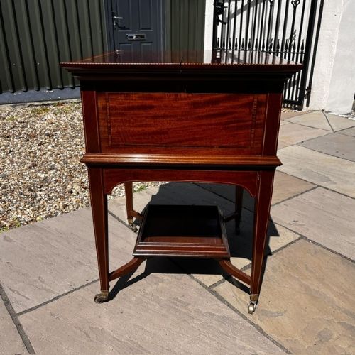 An Edwardian mahogany surprise drinks cabinet featuring satinwood inlay, square tapered legs, a lower shelf, and brass castors. View VII