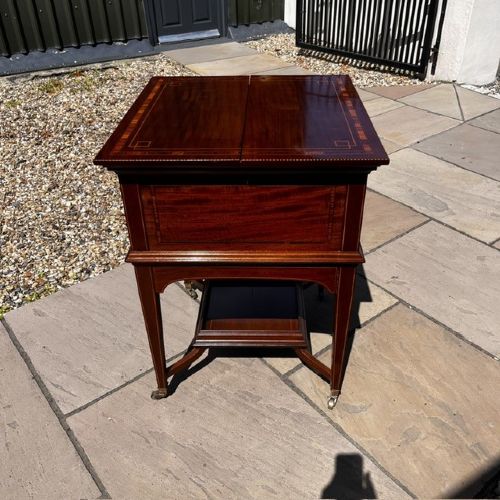 An Edwardian mahogany surprise drinks cabinet featuring satinwood inlay, square tapered legs, a lower shelf, and brass castors. View XI