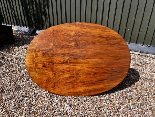 An oval Victorian walnut coffee table featuring a polished figured grain surface and a carved base. View V