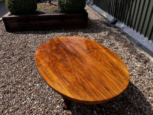 An oval Victorian walnut coffee table featuring a polished figured grain surface and a carved base. View VI