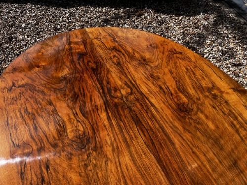 An oval Victorian walnut coffee table featuring a polished figured grain surface and a carved base. View VII