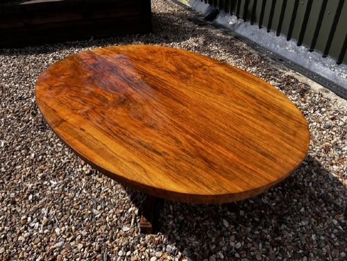 An oval Victorian walnut coffee table featuring a polished figured grain surface and a carved base. View IX