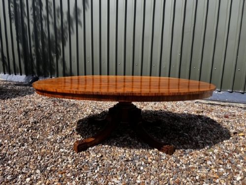 An oval Victorian walnut coffee table featuring a polished figured grain surface and a carved base. View XI