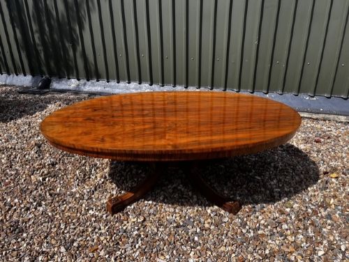 An oval Victorian walnut coffee table featuring a polished figured grain surface and a carved base. View XII