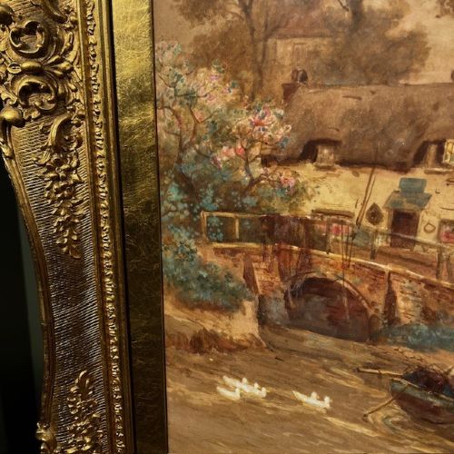 A 19th-century watercolour landscape painting depicting a river scene with boats and cottages, enclosed in an ornate giltwood frame. View VI