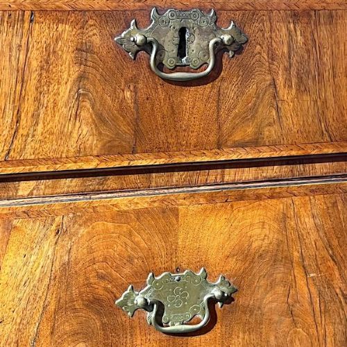 A George II period walnut chest on stand featuring multiple drawers with brass drop handles, supported by slender legs. View II