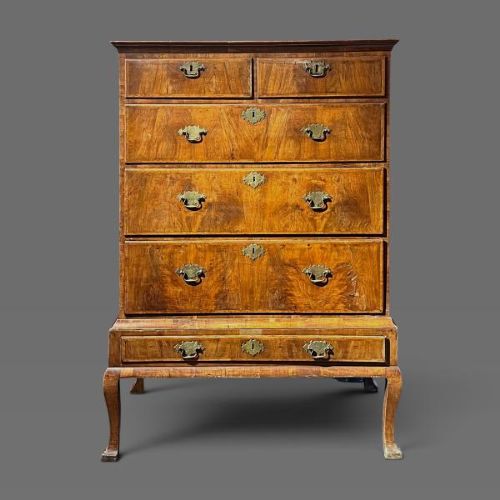 A George II period walnut chest on stand featuring multiple drawers with brass drop handles, supported by slender legs. View III