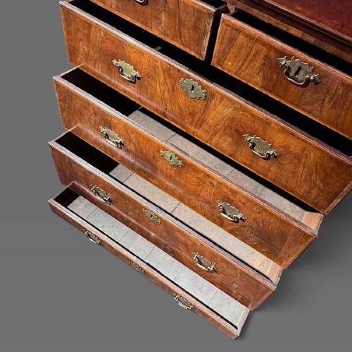 A George II period walnut chest on stand featuring multiple drawers with brass drop handles, supported by slender legs. View IV