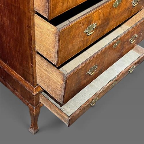 A George II period walnut chest on stand featuring multiple drawers with brass drop handles, supported by slender legs. View V