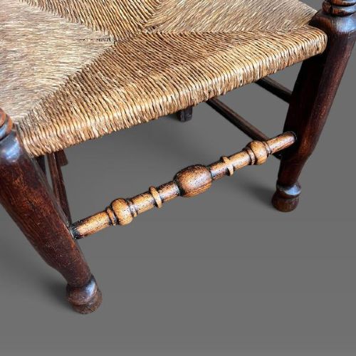 A set of ten dark oak Victorian Lancashire dining chairs with tiered spindle backrests and hand-woven rush seats. View II