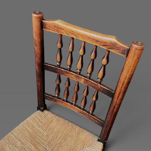 A set of ten dark oak Victorian Lancashire dining chairs with tiered spindle backrests and hand-woven rush seats. View VI
