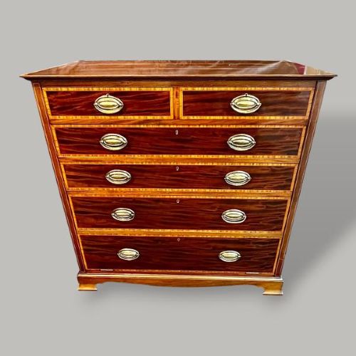 An Edwardian period Sheraton Revival mahogany tall chest featuring flame mahogany drawer fronts with inlay stringing and brass handles. View II