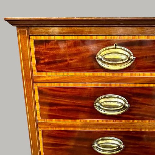 An Edwardian period Sheraton Revival mahogany tall chest featuring flame mahogany drawer fronts with inlay stringing and brass handles. View VI