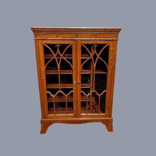 A late Victorian satinwood collectors cabinet featuring marquetry inlay details, Gothic style glazed double doors, and interior drawers. View II