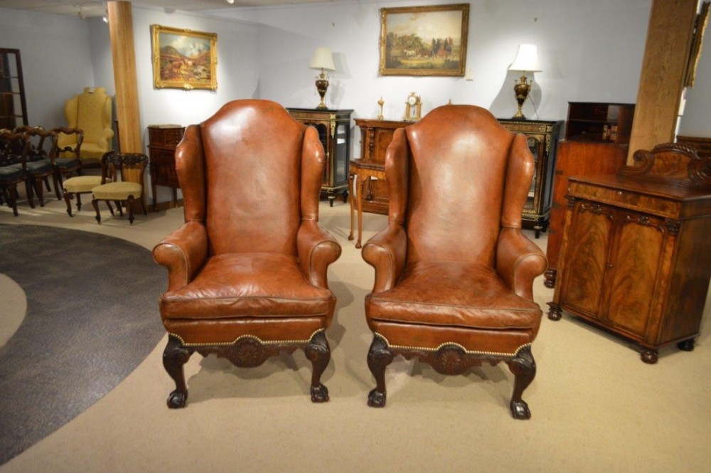 A good and large pair of Chippendale style brown leather wing armchairs.