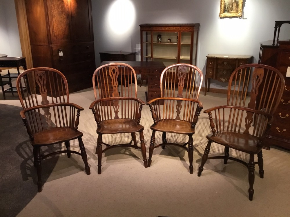 A harlequin set of four yew wood high back Windsor armchairs