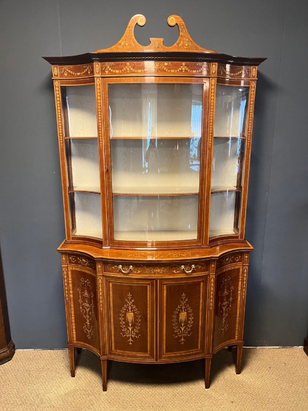 An exhibition quality antique inlaid serpentine display cabinet by Edwards and Roberts of London