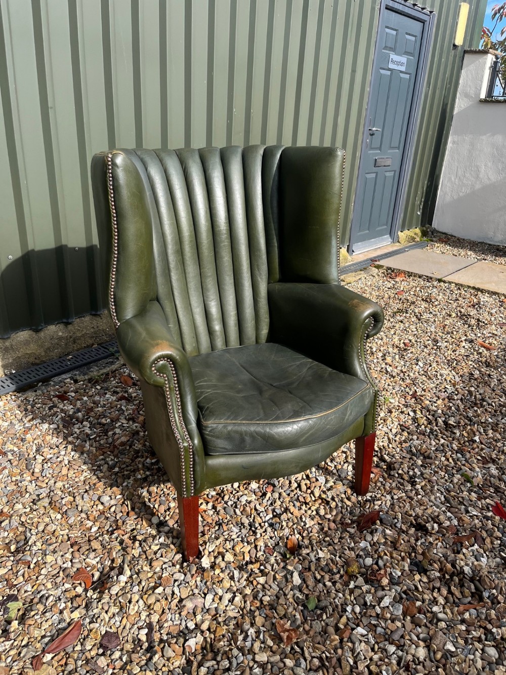 A Georgian Style barrel back green leather armchair.