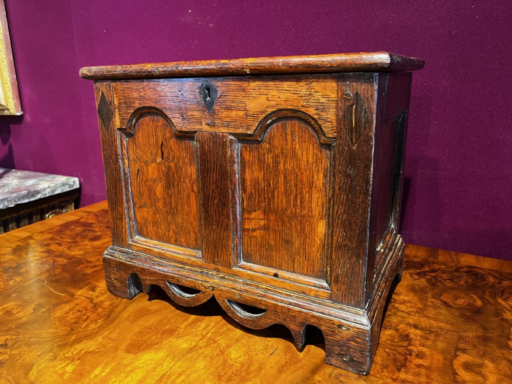 A late eighteenth-century miniature oak coffer with carved arched front panels, a kite-shaped inlay escutcheon, and a shaped apron base. View III