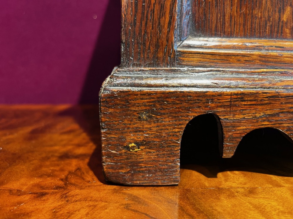 A late eighteenth-century miniature oak coffer with carved arched front panels, a kite-shaped inlay escutcheon, and a shaped apron base. View IX
