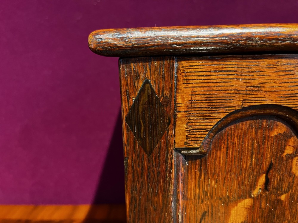 A late eighteenth-century miniature oak coffer with carved arched front panels, a kite-shaped inlay escutcheon, and a shaped apron base. View X