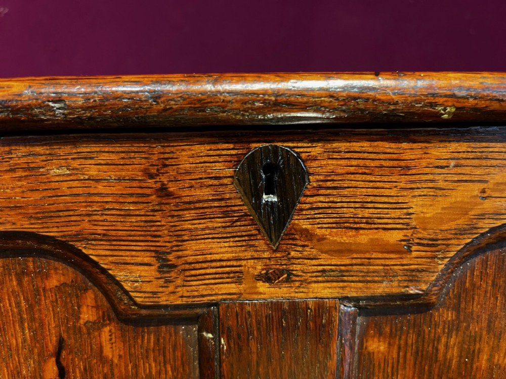 A late eighteenth-century miniature oak coffer with carved arched front panels, a kite-shaped inlay escutcheon, and a shaped apron base. View XI