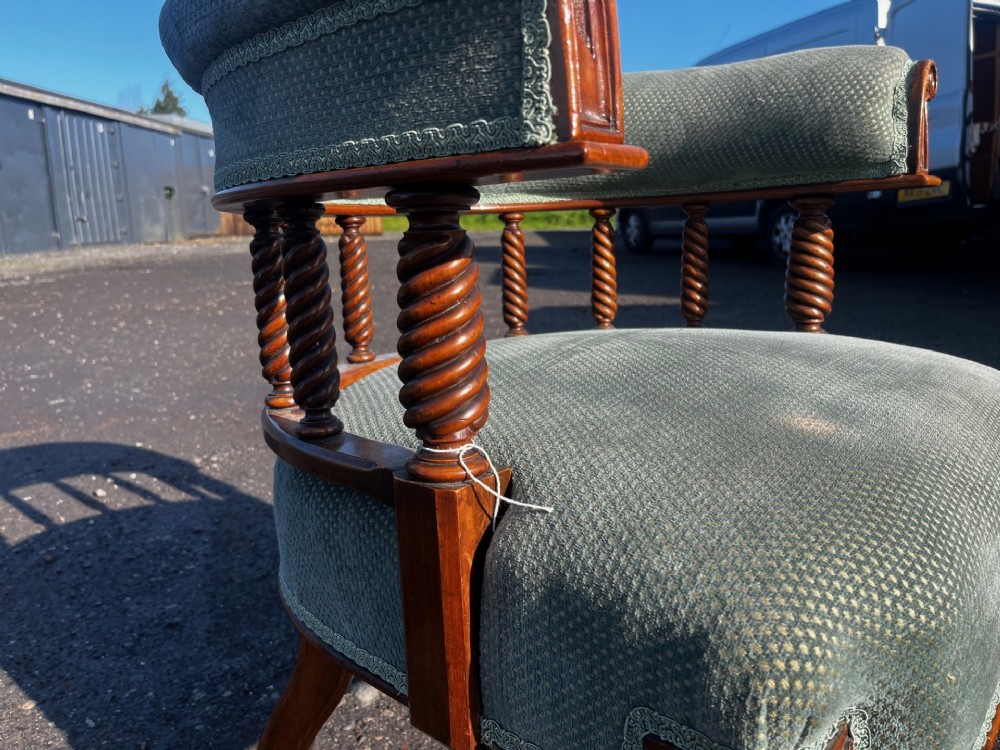 An antique Victorian walnut desk chair featuring a curved padded backrest, spiral-turned spindles, pale green textured upholstered seat, and turned legs on brass castors. View V