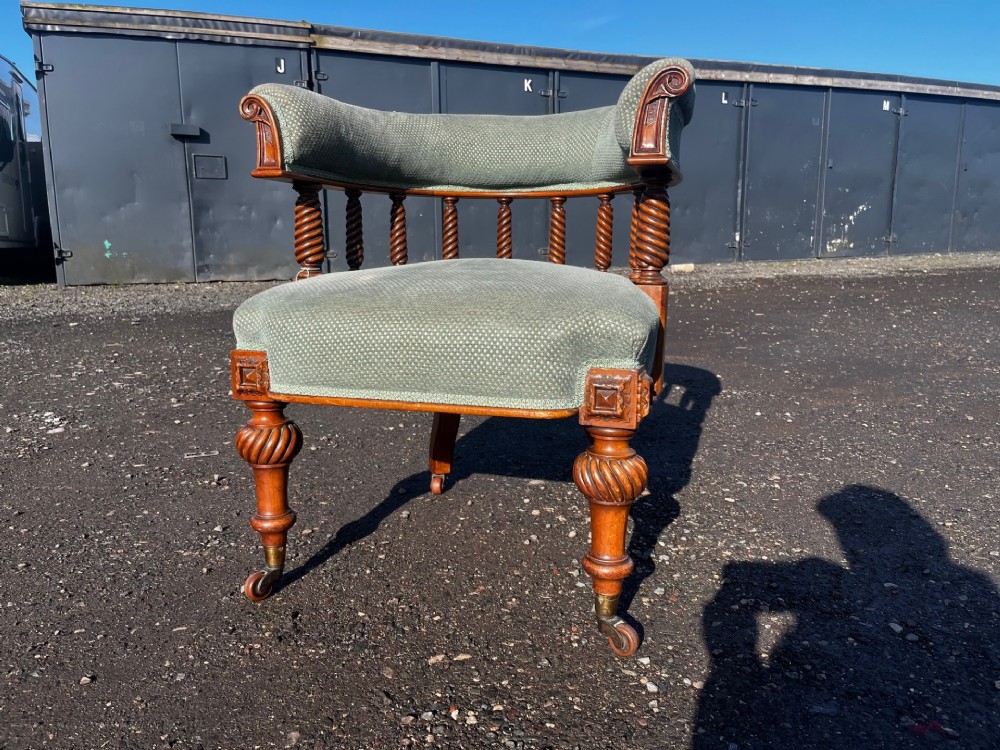 An antique Victorian walnut desk chair featuring a curved padded backrest, spiral-turned spindles, pale green textured upholstered seat, and turned legs on brass castors. View VI