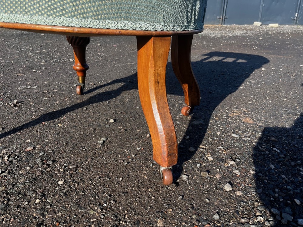 An antique Victorian walnut desk chair featuring a curved padded backrest, spiral-turned spindles, pale green textured upholstered seat, and turned legs on brass castors. View VIII