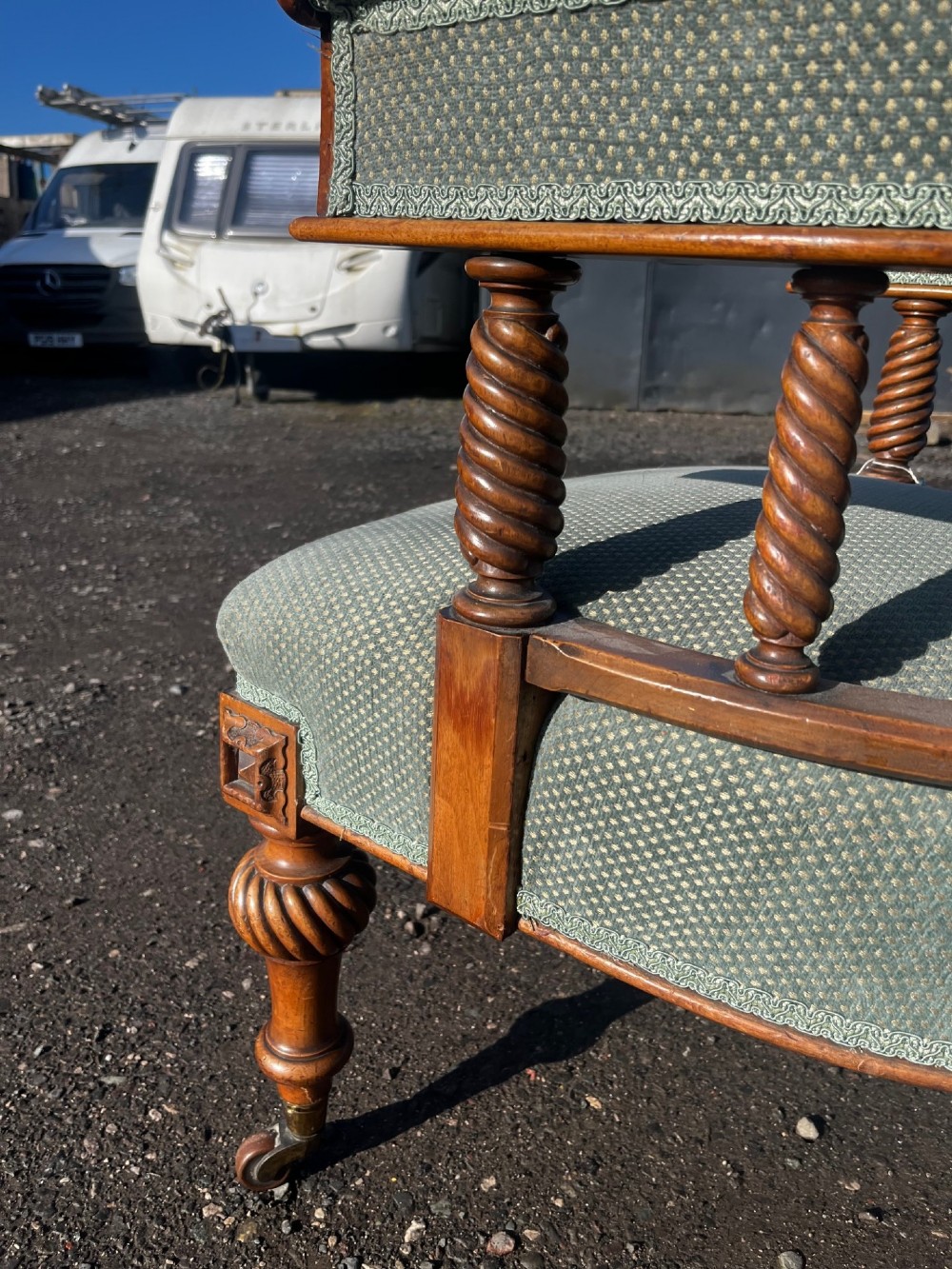 An antique Victorian walnut desk chair featuring a curved padded backrest, spiral-turned spindles, pale green textured upholstered seat, and turned legs on brass castors. View X