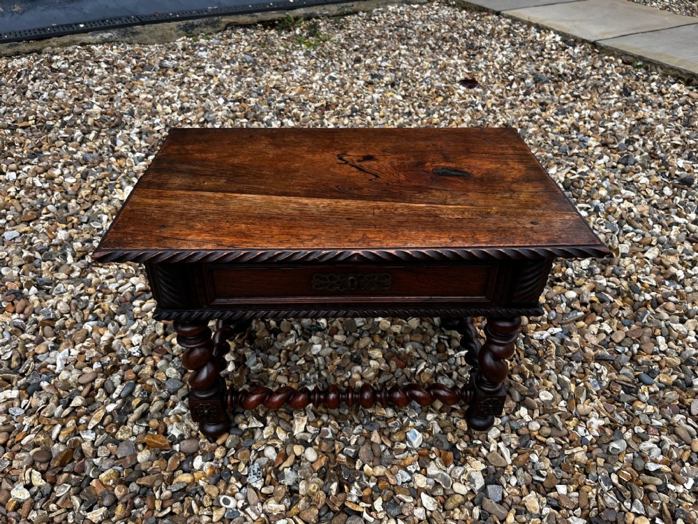 An early 19th-century Portuguese dark rosewood low table featuring spiral barley twist legs, carved rope moulding, and a single drawer with a brass keyhole escutcheon.