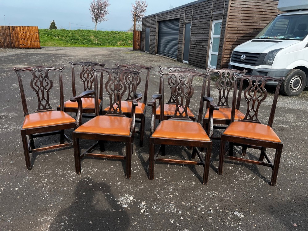 A set of late nineteenth-century mahogany Chippendale style dining chairs featuring intricately carved back splats and tan leather upholstered seats.
