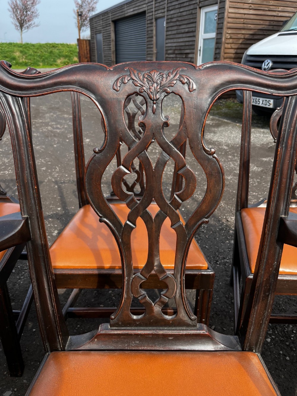 A set of late nineteenth-century mahogany Chippendale style dining chairs featuring intricately carved back splats and tan leather upholstered seats. View V