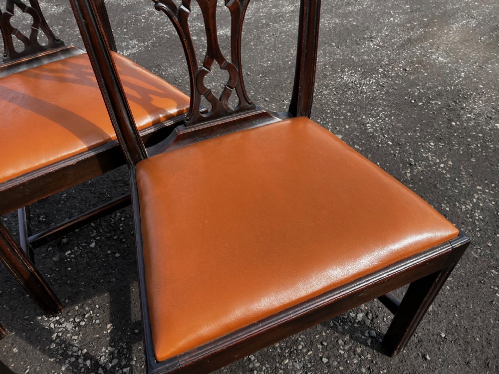 A set of late nineteenth-century mahogany Chippendale style dining chairs featuring intricately carved back splats and tan leather upholstered seats. View VI