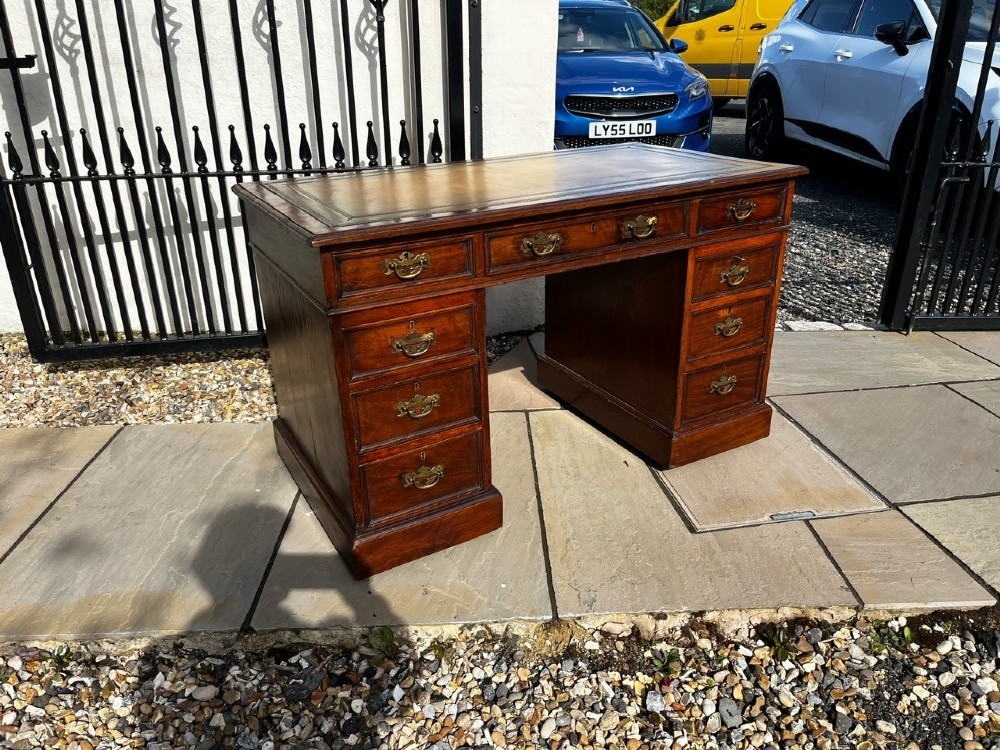 A late 19th-century mahogany pedestal desk featuring nine drawers with brass handles and a plinth base. View II
