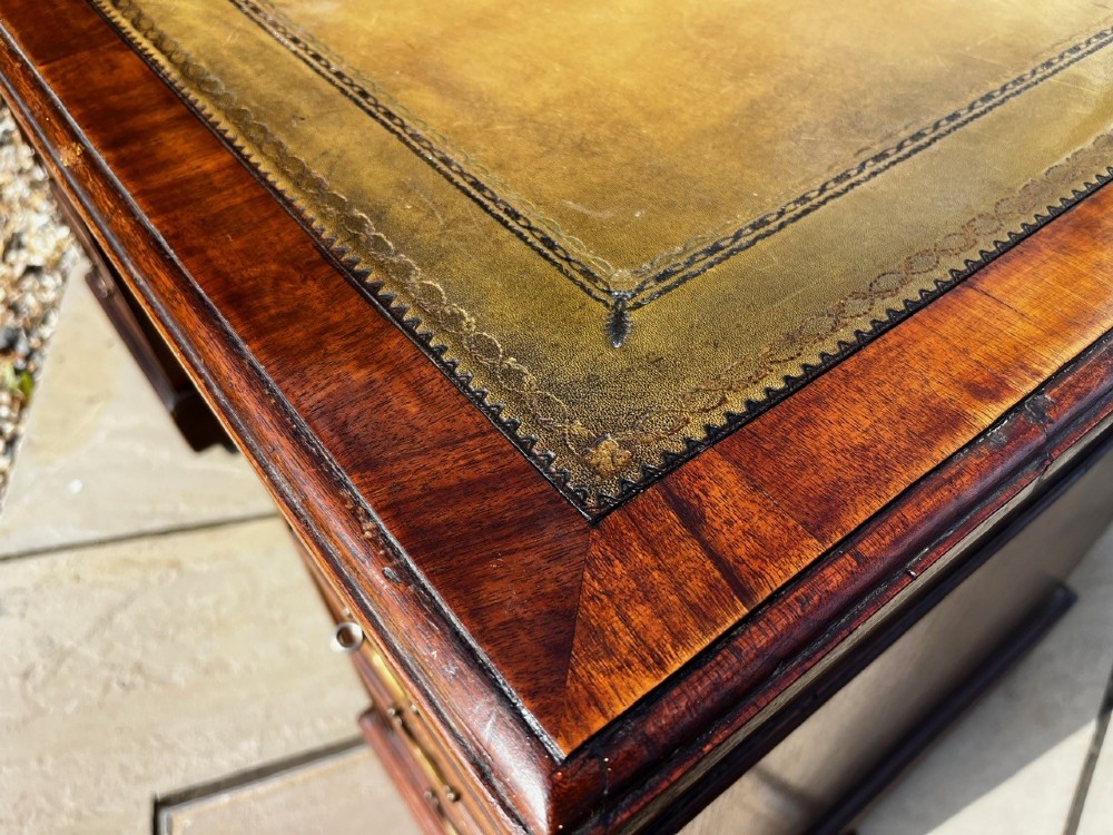 A late 19th-century mahogany pedestal desk featuring nine drawers with brass handles and a plinth base. View V